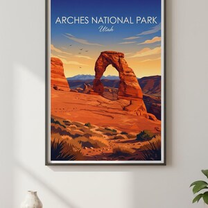 May include: Framed art print of Arches National Park in Utah. The artwork features a vibrant depiction of the iconic Delicate Arch under a blue sky with the text "Arches National Park Utah". The landscape is rendered in warm tones.
