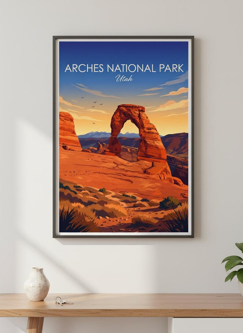May include: Framed art print of Arches National Park in Utah. The artwork features a vibrant depiction of the iconic Delicate Arch under a blue sky with the text "Arches National Park Utah". The landscape is rendered in warm tones.