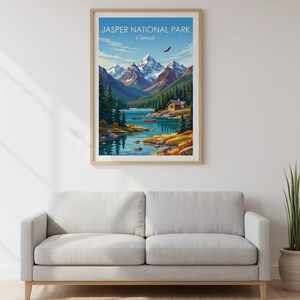 May include: A framed print of Jasper National Park, Canada, featuring a scenic landscape. The artwork depicts snow-capped mountains, a lake with red canoes, and a cabin. The sky is blue with a flying bird. The print is displayed above a gray sofa.