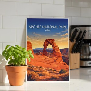 May include: A framed print of Arches National Park in Utah. The artwork depicts the iconic Delicate Arch in a vibrant landscape of red rock formations under a blue sky. Text at the top reads "Arches National Park Utah."
