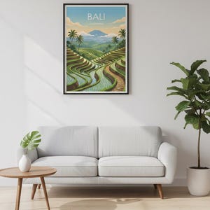 May include: A framed wall art print featuring a landscape illustration of Bali, Indonesia, with green terraced rice fields, palm trees, and a distant mountain under a soft sky. The text BALI Indonesia is printed at the top of the artwork.