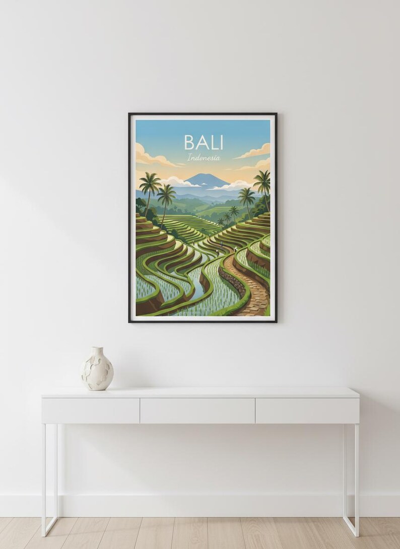 May include: A framed wall art print featuring a landscape illustration of Bali, Indonesia. The artwork depicts green terraced rice paddies, palm trees, and a distant mountain under a blue sky with clouds. The text BALI Indonesia is centered.