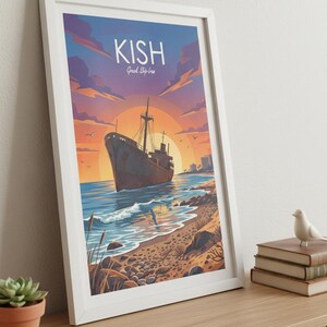 Op de afbeelding: Ingelijste kunstdruk met een vintage schip op een strand bij zonsondergang. De print heeft het woord "KISH" bovenaan, met "Greek Ship-Ira" eronder. Het kunstwerk zit in een witte lijst en wordt op een houten oppervlak weergegeven.