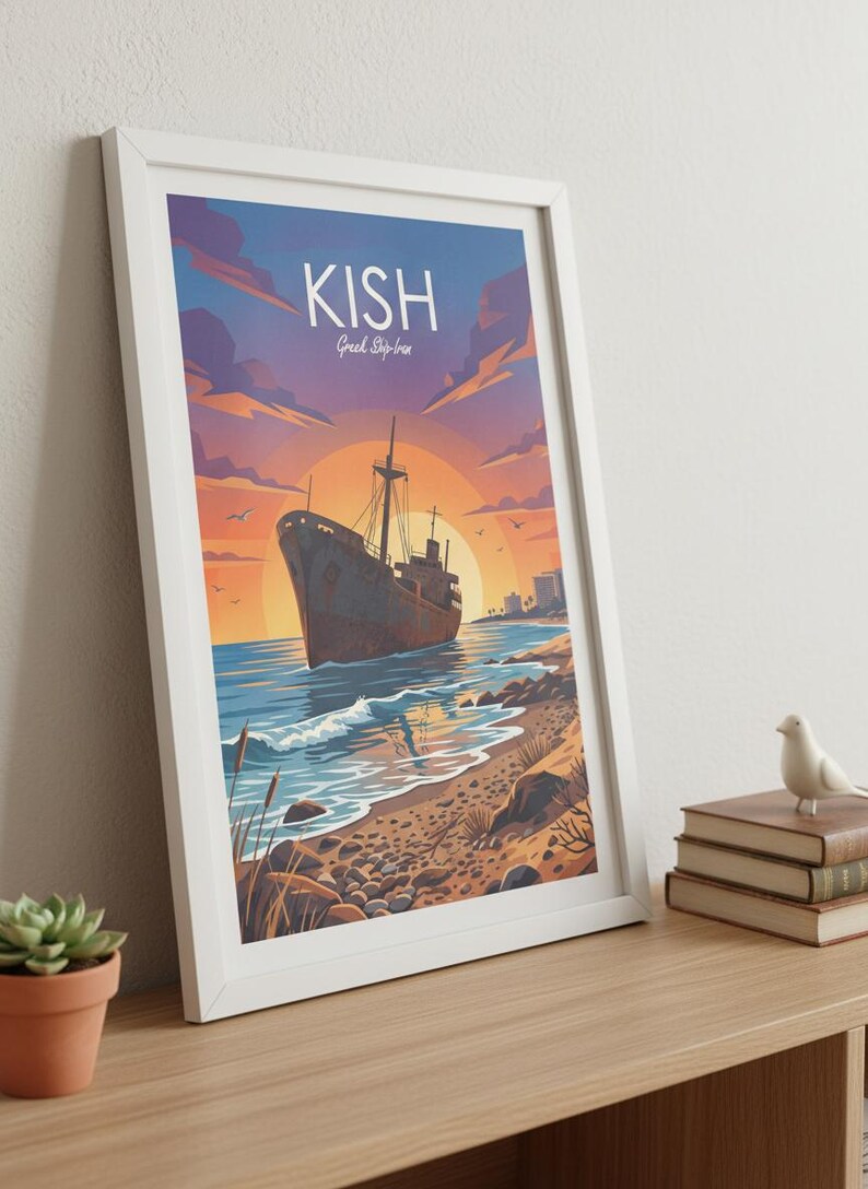 Op de afbeelding: Ingelijste kunstdruk met een vintage schip op een strand bij zonsondergang. De print heeft het woord "KISH" bovenaan, met "Greek Ship-Ira" eronder. Het kunstwerk zit in een witte lijst en wordt op een houten oppervlak weergegeven.