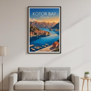 May include: Framed art print of Kotor Bay, Montenegro. The artwork depicts a coastal town with boats on the water, surrounded by mountains. The sky transitions from orange to blue. The text "KOTOR BAY Montenegro" is at the top.