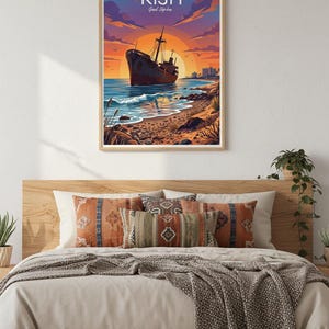 Op de afbeelding: Een rechthoekige wandkunstprint met een gestileerde illustratie van een scheepswrak op een strand bij zonsondergang. De tekst KISH en Greek Ship-Iron staat bovenaan gedrukt. De sc&egrave;ne toont een donkere scheepsromp, een oranje zon en een rotsachtige kust.