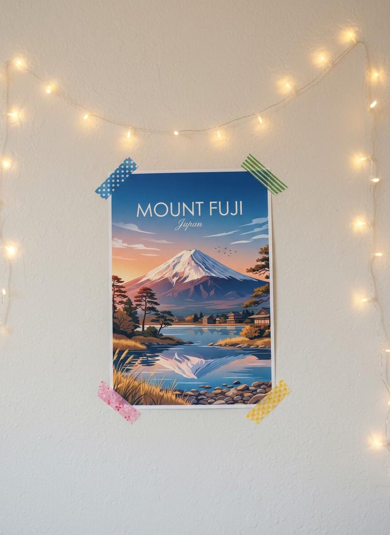 May include: A poster of Mount Fuji, Japan, is taped to a white wall with decorative string lights. The artwork depicts the mountain at sunset, with a lake and trees in the foreground. The text "MOUNT FUJI Japan" is at the top.
