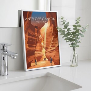 May include: A framed vertical art print featuring a stylized illustration of Antelope Canyon, Arizona, USA. The image depicts orange sandstone rock formations with a light beam and three small figures, with the text ANTELOPE CANYON Arizona, USA.