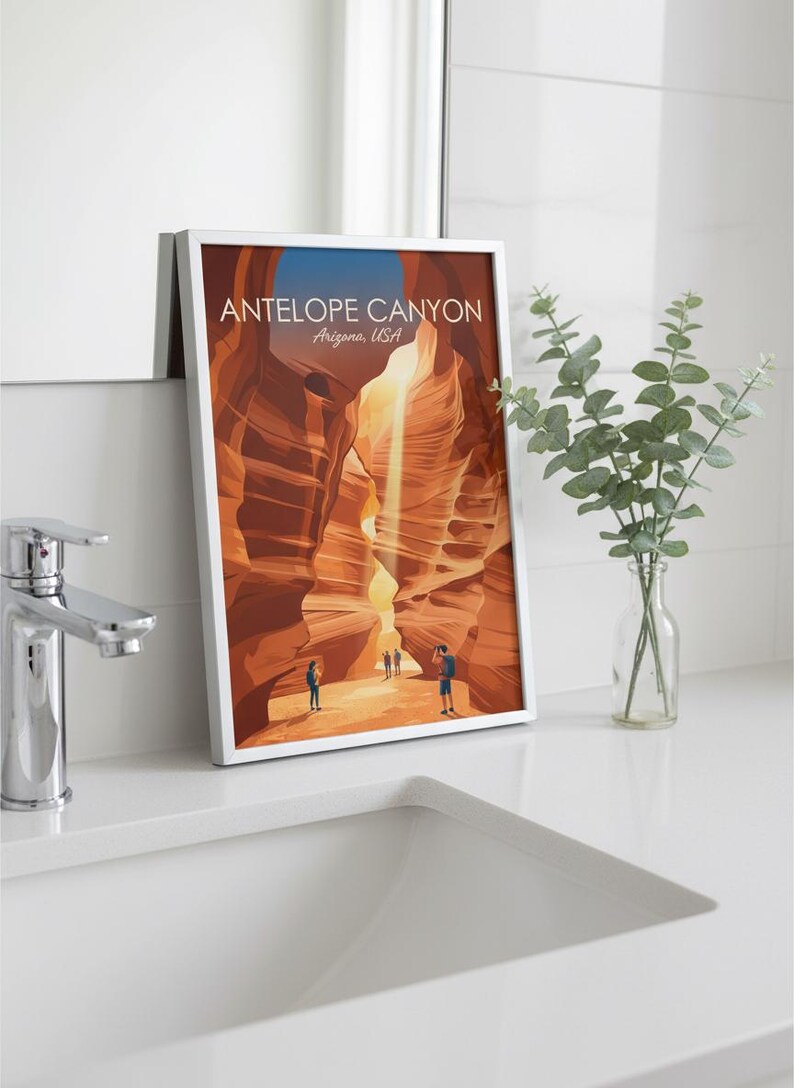 May include: A framed vertical art print featuring a stylized illustration of Antelope Canyon, Arizona, USA. The image depicts orange sandstone rock formations with a light beam and three small figures, with the text ANTELOPE CANYON Arizona, USA.