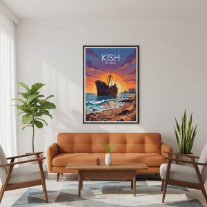 Op de afbeelding: Een ingelijste kunstafdruk met een scheepswrak op een strand bij zonsondergang. Het kunstwerk toont een bruin schip, blauw water en een levendige oranje en paarse lucht. Het woord "KISH" staat bovenaan de afdruk.