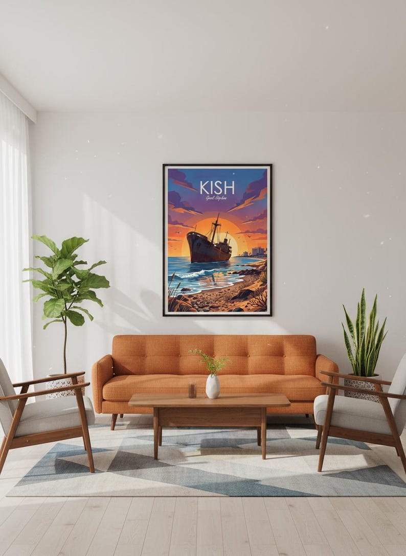 Op de afbeelding: Een ingelijste kunstafdruk met een scheepswrak op een strand bij zonsondergang. Het kunstwerk toont een bruin schip, blauw water en een levendige oranje en paarse lucht. Het woord "KISH" staat bovenaan de afdruk.