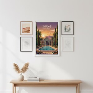 May include: A wall display featuring framed art prints and a wooden bench. The central piece is a framed poster with the text "Shiraz Eram Garden" depicting a Persian garden scene with a pool and palm trees. Other frames contain abstract and landscape art.