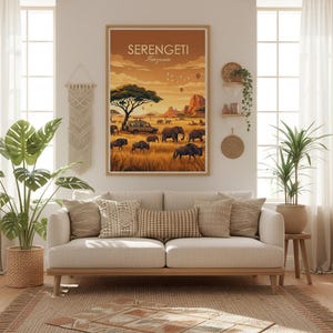 May include: A framed art print featuring a Serengeti landscape with elephants, a safari vehicle, and hot air balloons under a warm, golden sky. The print is displayed above a beige sofa with decorative pillows, creating a cozy living room scene.