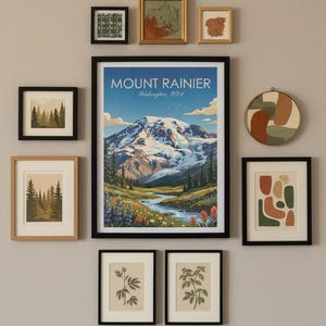 May include: A gallery wall arrangement featuring framed art prints. The central piece is a Mount Rainier poster with a mountain landscape. Other prints include forest scenes, botanical illustrations, and abstract art. The frames are black and natural wood.