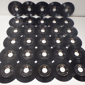 Puede incluir: Una colección de 30 discos de vinilo negros dispuestos en un patrón circular. Los discos son todos del mismo tamaño y tienen una etiqueta en el centro. Los discos están todos en buen estado y no tienen arañazos ni daños.