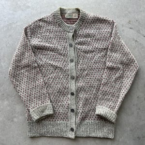 May include: A gray cardigan sweater with a button-up front. The sweater has a textured pattern with small red dots. The collar, cuffs, and button placket are a solid gray color. The label reads "L.L.Bean".