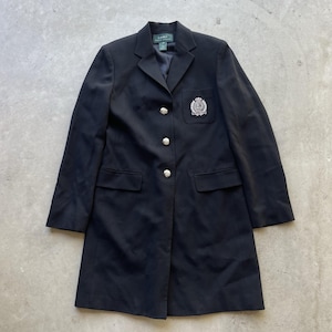 May include: A black blazer with a crest emblem on the chest. The blazer has three silver buttons and two front pockets. The blazer is a long style, and the brand name "Lauren" is visible on the label.