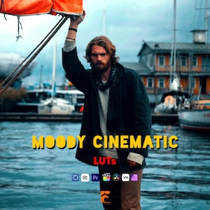 May include: A man with a beard and long hair stands near a body of water, holding a rope attached to an orange sail. The image has text that reads "MOODY CINEMATIC LUTS" in yellow letters. The background includes boats and buildings.
