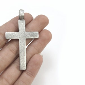 May include: A silver cross pendant with a textured finish.