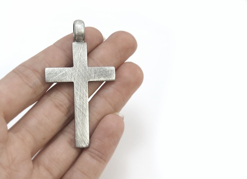 May include: A silver cross pendant with a textured finish.