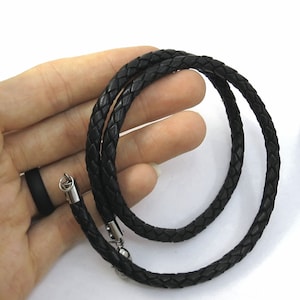May include: A black leather cord necklace with a silver clasp. The cord is braided and has a smooth texture.