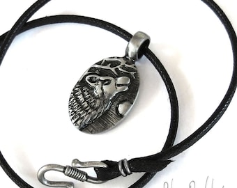 May include: A silver pendant necklace with a wolf howling at the moon design. The pendant is oval shaped and has a black leather cord.