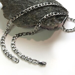 May include: A silver curb chain necklace with a lobster clasp closure.