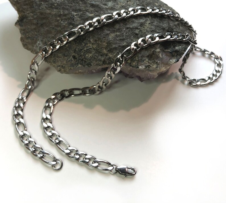 May include: A silver curb chain necklace with a lobster clasp closure.