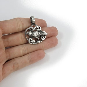 Pu&ograve; includere: Ciondolo in argento con un designo di corvo dettagliato all'interno di un nodo celtico. Il ciondolo &egrave; un simbolo celtico tradizionale di saggezza e conoscenza.
