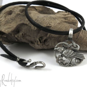 Pu&ograve; includere: Una collana con un ciondolo in argento che presenta un designo di corvo dettagliato con un nodo celtico. La collana &egrave; su un cordoncino nero con una chiusura a gancio in argento.