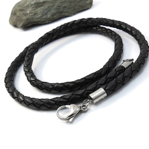 May include: Black leather cord necklace with a silver clasp. The cord is braided and has a smooth texture.