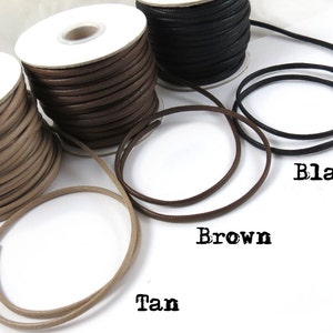 May include: Three spools of leather cord in tan, brown, and black. The cords are wound around white spools. The cords are shown in a circle around the spools.