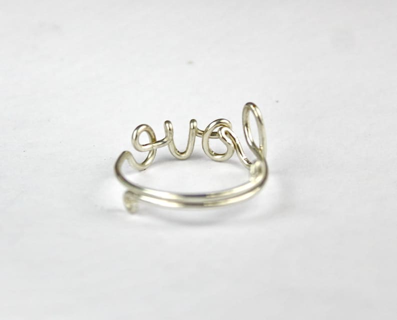 K&ouml;nnte beinhalten: Ein Ring aus Silberdraht mit dem Wort "love" in Kursivschrift.