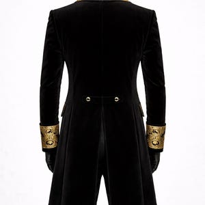 May include: Black velvet coat with gold embroidered collar and cuffs. The long coat features a tailored fit, with gold button details on the back and cuffs. The sleeves are long and fitted. The coat is a formal style.