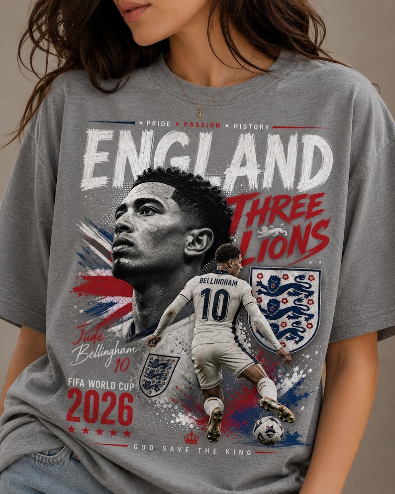 Puede incluir: Una camiseta gris con un estampado gr&aacute;fico de Jude Bellingham. El dise&ntilde;o incluye el texto "ENGLAND", "THREE LIONS", "Jude Bellingham 10", "FIFA WORLD CUP 2026" y "GOD SAVE THE KING", junto a un jugador de f&uacute;tbol, un escudo y un bal&oacute;n.