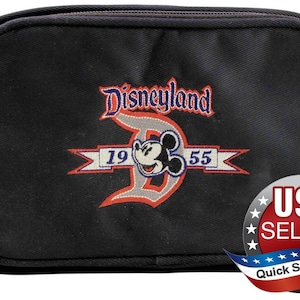 May include: A black rectangular zippered pouch featuring an embroidered Disneyland logo with a large letter D, the year 1955, and a Mickey Mouse graphic in the center. The design uses red, white, blue, and black thread on a solid black fabric base.