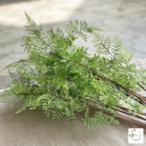 Faux evergreen branch decorating a holiday table centerpiece