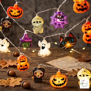 May include: A string of Halloween LED lights featuring various plastic figures including orange jack-o'-lanterns, white ghosts, a mummy, a black cat, a witch, a skull, and a purple spider web with a spider, all connected by a thin clear wire.