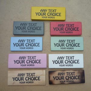 Peut inclure: Une collection de neuf panneaux rectangulaires en bois de différentes couleurs, notamment jaune, gris, rouge, bleu, vert, rose, blanc, bois naturel et bois teinté foncé. Chaque panneau porte le texte imprimé en noir ANY TEXT YOUR CHOICE YOUR WORDS.
