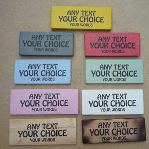 May include: A selection of rectangular wooden signs in various colours, including yellow, grey, red, blue, green, pink, white, and natural wood. Each sign has the text "ANY TEXT YOUR CHOICE YOUR WORDS" in black.