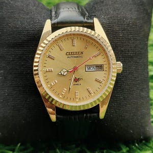 Pode incluir: Um conjunto de três canecas de cerâmica com esmalte salpicado creme. Cada caneca apresenta um design pintado à mão diferente: uma folha azul e verde, uma flor amarela e uma baga vermelha. As canecas têm uma forma simples e arredondada.