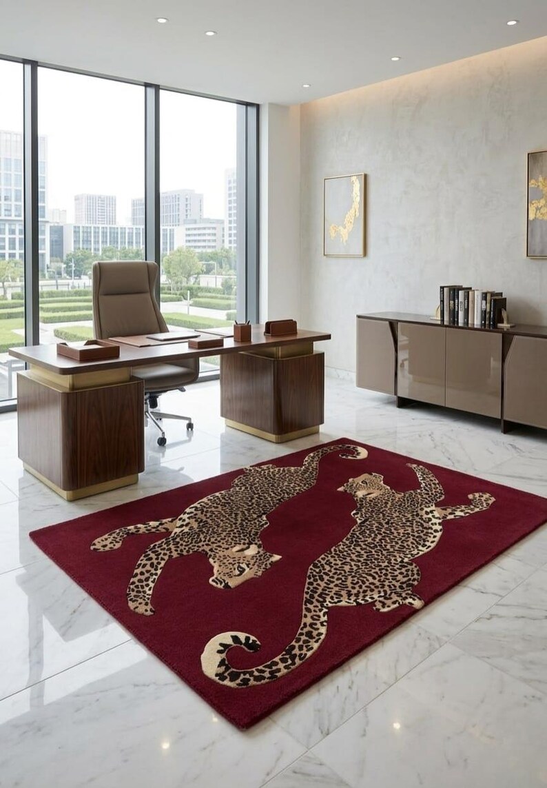 May include: A rectangular area rug featuring a deep burgundy background with two large, detailed leopard illustrations in shades of tan, brown, and black. The leopards are depicted in a dynamic, sprawling pose across the center of the rug.