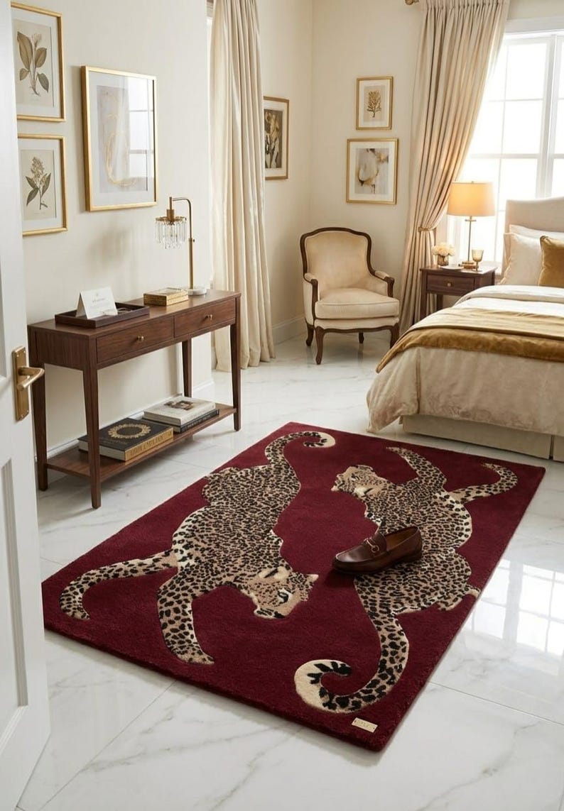 May include: A rectangular area rug featuring a deep burgundy background with two large, mirrored leopard illustrations in tan and black spots. The rug is positioned on a white marble floor, and a single brown leather loafer rests on its surface.