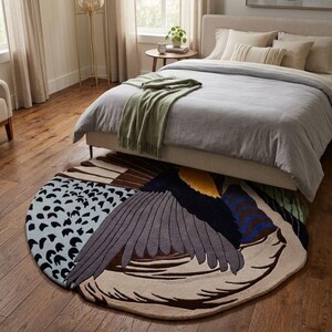 K&ouml;nnte beinhalten: Ein gro&szlig;er, runder Teppich mit einem stilisierten Vogelfl&uuml;gel-Design. Der Teppich zeigt eine Farbpalette aus Hellblau mit schwarzen Punkten, Dunkelgrau, Braun, Creme, Gelb und Blau. Die Fl&uuml;gelfedern sind in geschichteten, gebogenen Abschnitten dargestellt.