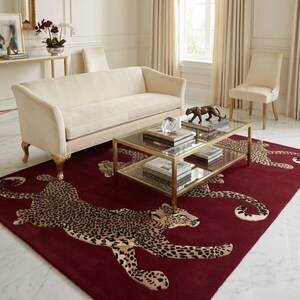 May include: A rectangular area rug featuring a deep burgundy background with multiple repeating leopard motifs in shades of tan, brown, and black. The rug is positioned on a white marble floor, showcasing a large-scale animal print pattern.