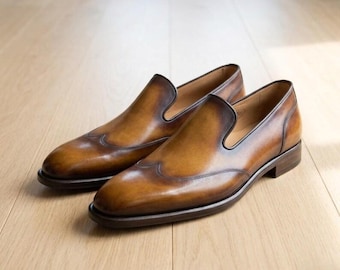 Zapatos de vestir tipo mocasín con puntera de ala, de cuero color mostaza, hechos a mano para hombre.