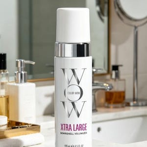 Pu&ograve; includere: Una bottiglia bianca di Color Wow Xtra Large Bombshell Volumizer, 195 ml, con dettagli argentati. La bottiglia ha un tappo bianco e il nome del marchio &egrave; stampato in argento. Il prodotto &egrave; esposto in un bagno.