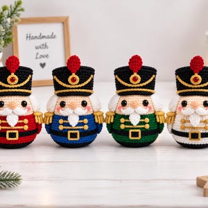 Peut inclure: Quatre poupées casse-noisette au crochet avec des chapeaux noirs à plumes rouges, des garnitures dorées et des corps ronds. Chaque poupée a une barbe blanche, des yeux noirs et des joues roses. Elles sont rouges, bleues, vertes et blanches.