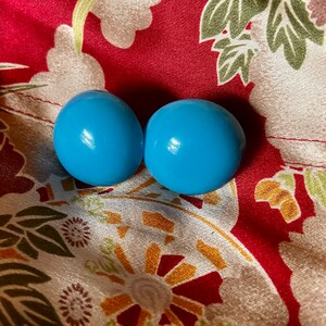 May include: Two light blue round ceramic knobs with a glossy finish.