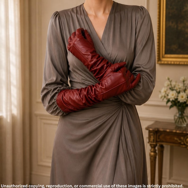Woman wearing red ruched long leather opera gloves with center seam detailing, styled with an elegant taupe evening dress.